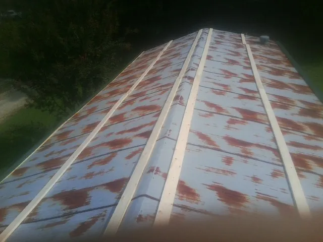 Rusted metal roof panels with new wood purlins before replacement — Storm Damage Roof Repair in West Warren by Roofing Brothers