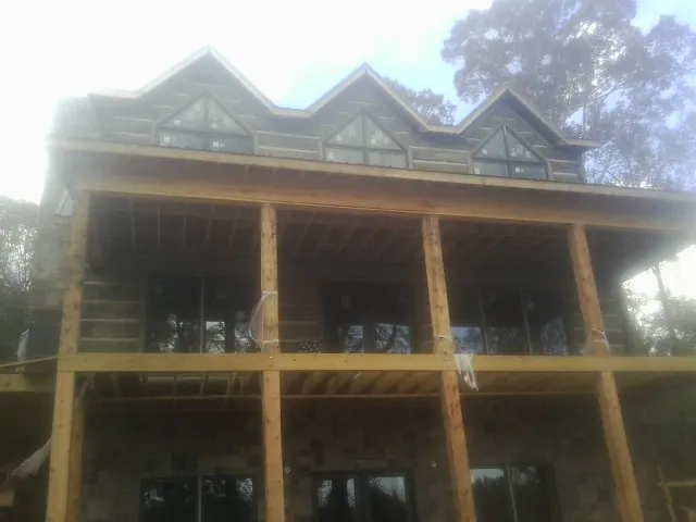 Dormers and porch framing on a large log home under construction — Roof Coating work by our crew in West Warren