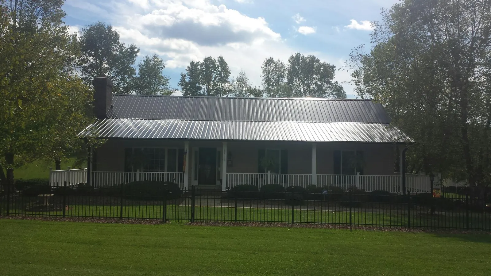 Gray metal roof on a brick ranch with a full width front porch — Gutter Guard Installation work by our crew in West Warren