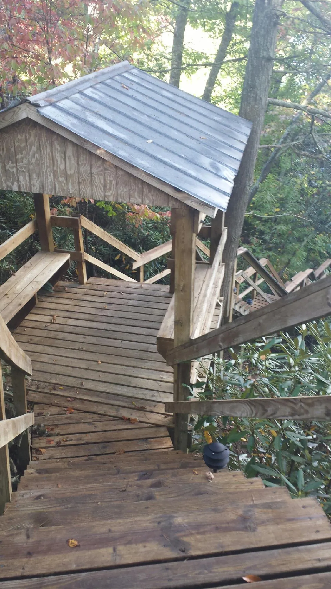 Metal roofed shelter over wooden steps on a wooded walkway — Skylight Repair & Installation work by our crew in West Warren