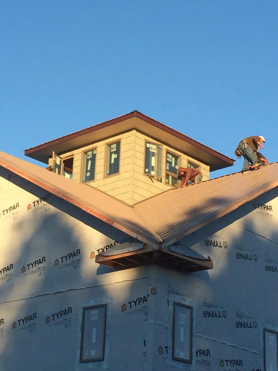 Roofers working around a rooftop cupola on a new metal roof at sunset — Roof Waterproofing in West Warren by Roofing Brothers